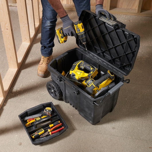 STANLEY STST33090-1 gereedschapskist op wielen open met gele elektrisch gereedschap en handgereedschap op bouwplaats.