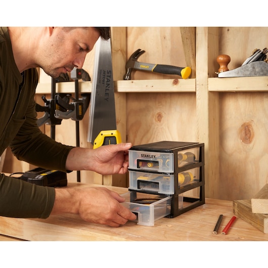 Photo des tiroirs de rangement STANLEY STST40710-1 sur un établi, remplis d’outils à main en atelier.