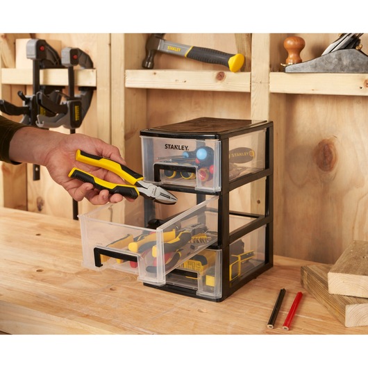 STANLEY STST40711-1 organiseur à trois tiroirs, photo dans un atelier avec une main tenant des pinces.