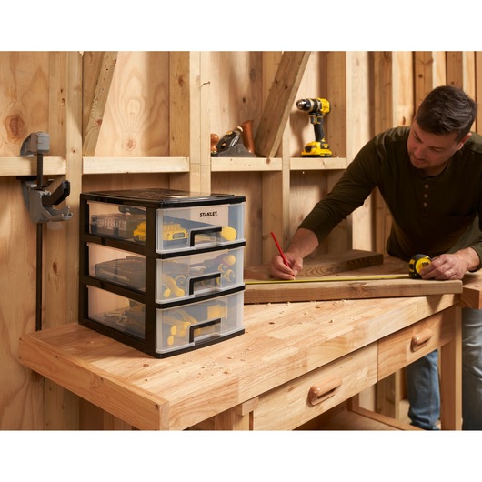 STANLEY STST40712-1 organisateur à tiroirs en plastique sur établi en bois, rempli d’outils, dans un atelier.