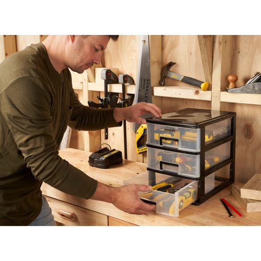 STANLEY STST40712-1 organiseur à trois tiroirs transparents sur un établi, rangement d'outils à main.