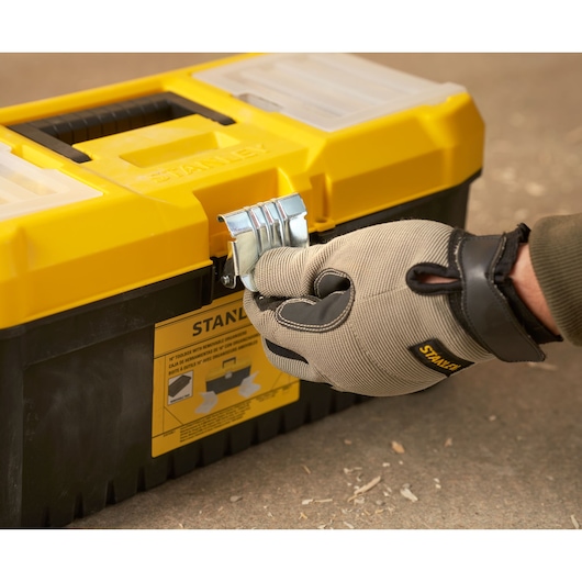 Stanley STST75785-1 gereedschapskist geel-zwart, voorkant, handschoenhand opent sluiting.