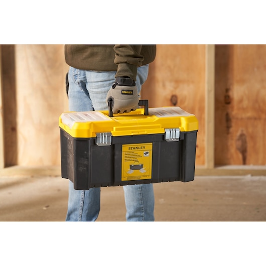 Photo de la boîte à outils STANLEY STST75787-1 avec couvercle jaune, base noire, portée à la main, vue avant.