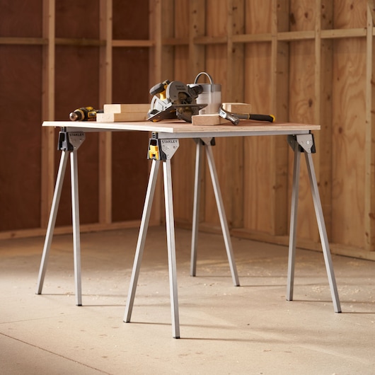 STANLEY STST81337-1 opvouwbare zaagboktafel in werkplaats met gereedschap en houten blokken erop.
