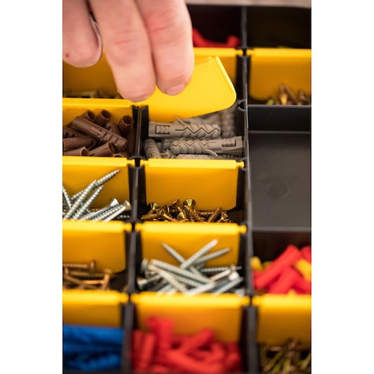 STANLEY STST81680-1 photographie d'une main ouvrant une boîte jaune avec vis et chevilles assorties.