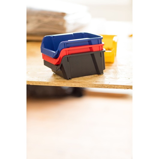 STANLEY STST82737-1 bacs empilables en plastique noir, rouge et bleu, angle latéral sur surface en bois.