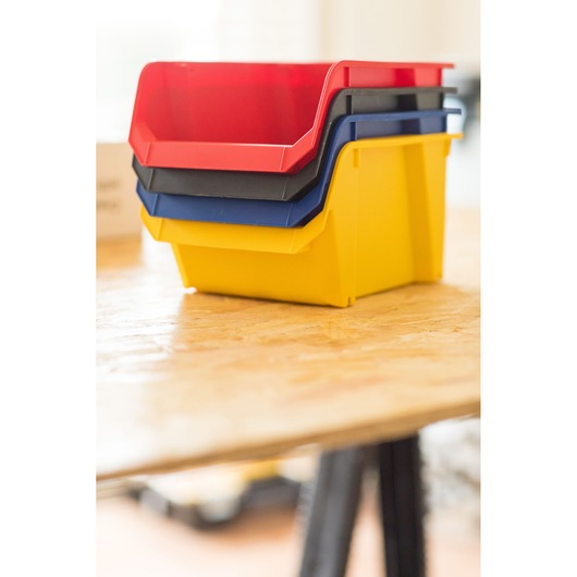 STANLEY STST82739-1 bacs de rangement empilables en plastique rouge, noir, bleu et jaune sur table en bois, angle latéral.