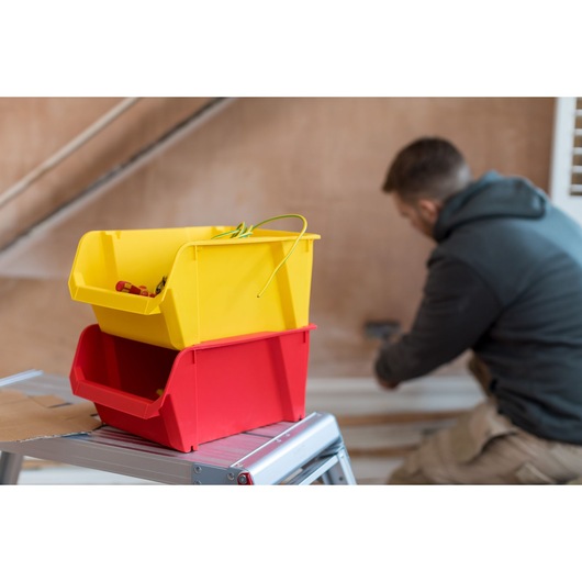 Photographie STANLEY STST82742-1 de bacs de rangement jaunes et rouges sur escabeau métallique en intérieur.