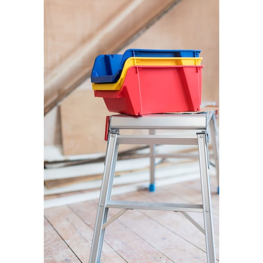 STANLEY STST82742-1 bacs de rangement empilables en plastique rouge, jaune et bleu sur établi en métal.