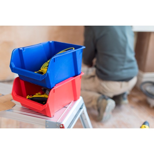 STANLEY STST82743-1 photographie de bacs de rangement rouges et bleus sur un escabeau, contenant outils et câbles.