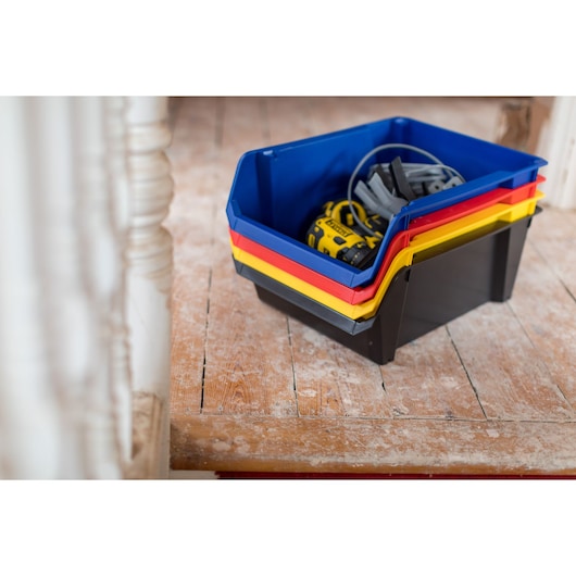 STANLEY STST82746-1 bacs de rangement empilables bleu, rouge, jaune et noir contenant des outils, photo en intérieur.