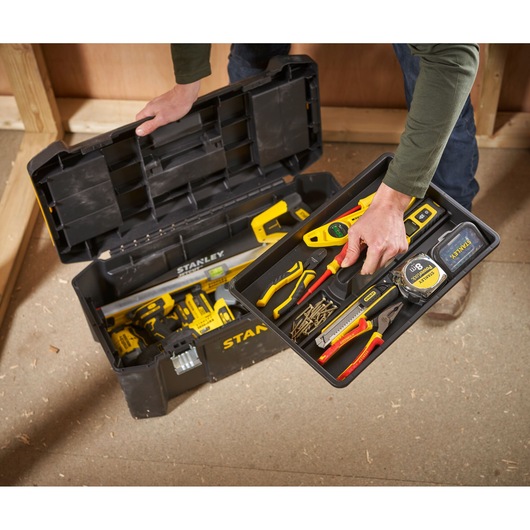 STANLEY STST82976-1 boîte à outils avec couvercle ouvert montrant des outils à main organisés et accessoires, vue de dessus en atelier.