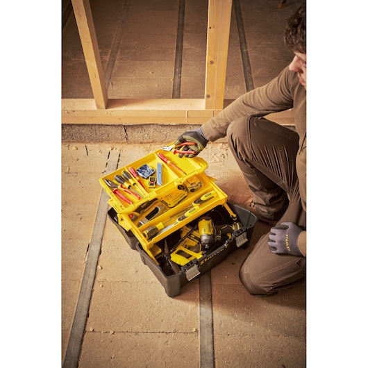 STANLEY STST83397-1 gereedschapskist met gele trays en diverse gereedschappen, foto van product op bouwplaats.