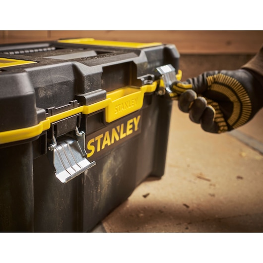STANLEY STST83397-1 zwarte en gele gereedschapskist met metalen sluitingen, werknemer opent frontsluiting.
