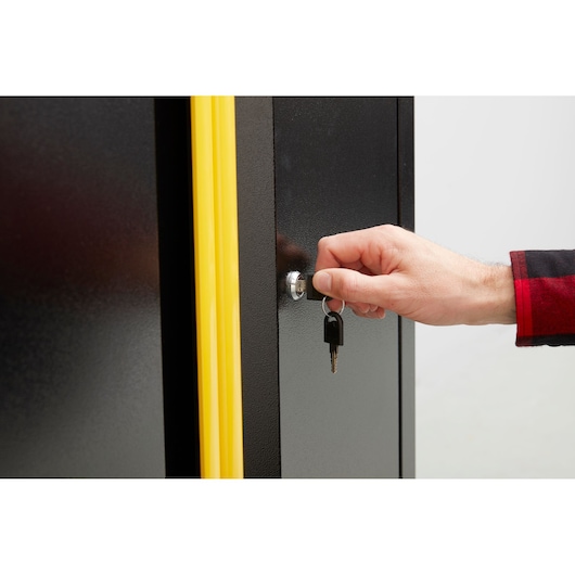 STANLEY STST97595-1 kast met gele rand, close-up van slot en hand met sleutel, productfotografie.
