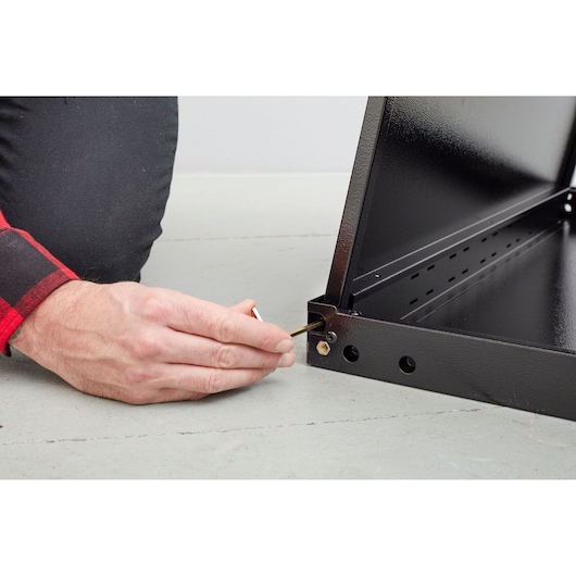 STANLEY STST97595-1 persoon monteert zwart metalen frame met inbussleutel, close-up van hand en hoekverbinding.