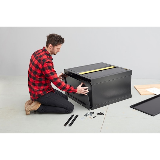 STANLEY STST97595-1 zwarte gereedschapskist wordt gemonteerd met beslag en panelen op de vloer.