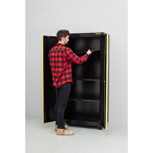 Photo de l’armoire STANLEY STST97957-1 avec portes ouvertes, personne ajustant l’étagère supérieure.