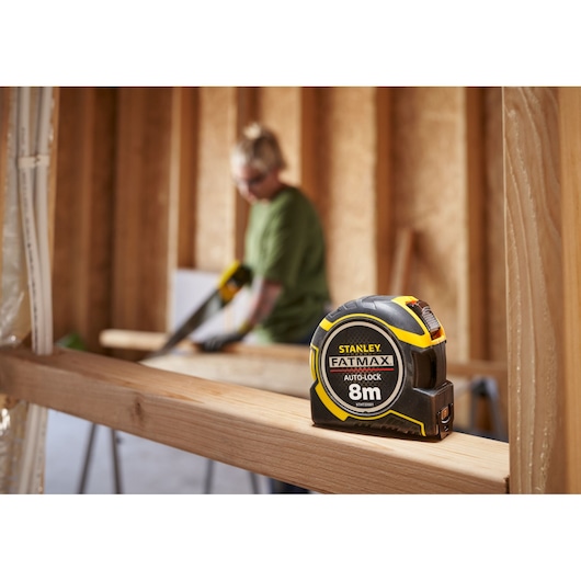 STANLEY XTHT0-33501 rolmaat zwart en geel op houten balk, FATMAX 8m Auto-Lock, bouwplaats.