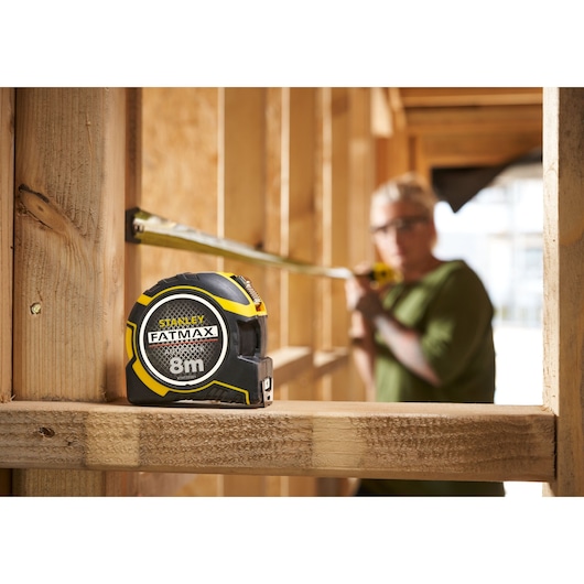 Foto van STANLEY FATMAX XTHT0-33501 8m rolmaat op houten frame bij bouwplaats.