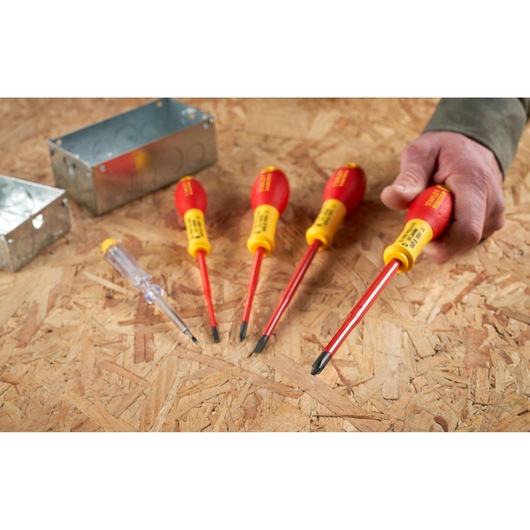STANLEY XTHT0-62692 geïsoleerde schroevendraaierset met rood-gele handgrepen op houten ondergrond, hand houdt een gereedschap vast.